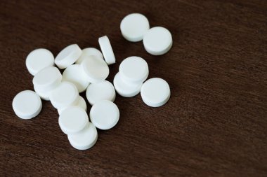 Yukarıdan bir sürü ilaç ve beyaz hap geliyor, ahşap arka planda düşüyor. ağrı kesiciler ve uyuşturucu kullanımı kavramı.