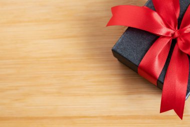 Hediye kutusu Koyu Gri Yeni Yıl. Kırmızı kurdeleli hediye konteynırı. Vintage Matte siyah tahta arka planı..