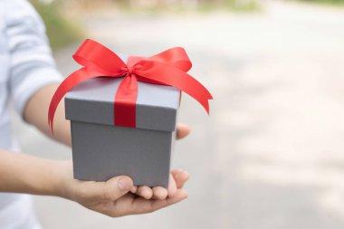 Kadın elleri hediye kutusunu tutuyor. Siyah pakette güzel kırmızı kurdele var. Fotokopi alanı ile sürpriz özel etkinlik için. Noel, doğum günü ya da yeni yıl konsepti. Yüksek çözünürlüklü ürün.