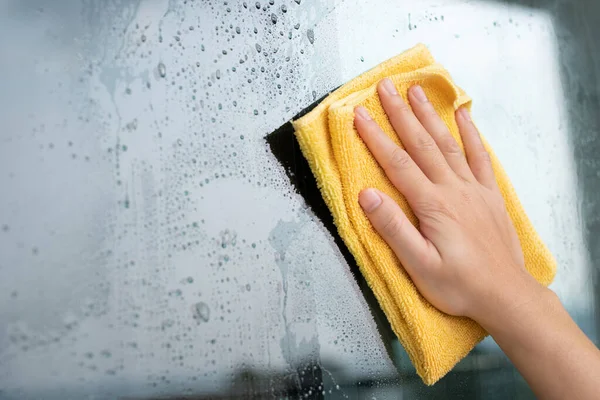 布の特別なラグ黄色でガラス窓を掃除のシートの上に手のガラスクリーナーを閉じます 細菌やウイルスの洗浄 — ストック写真
