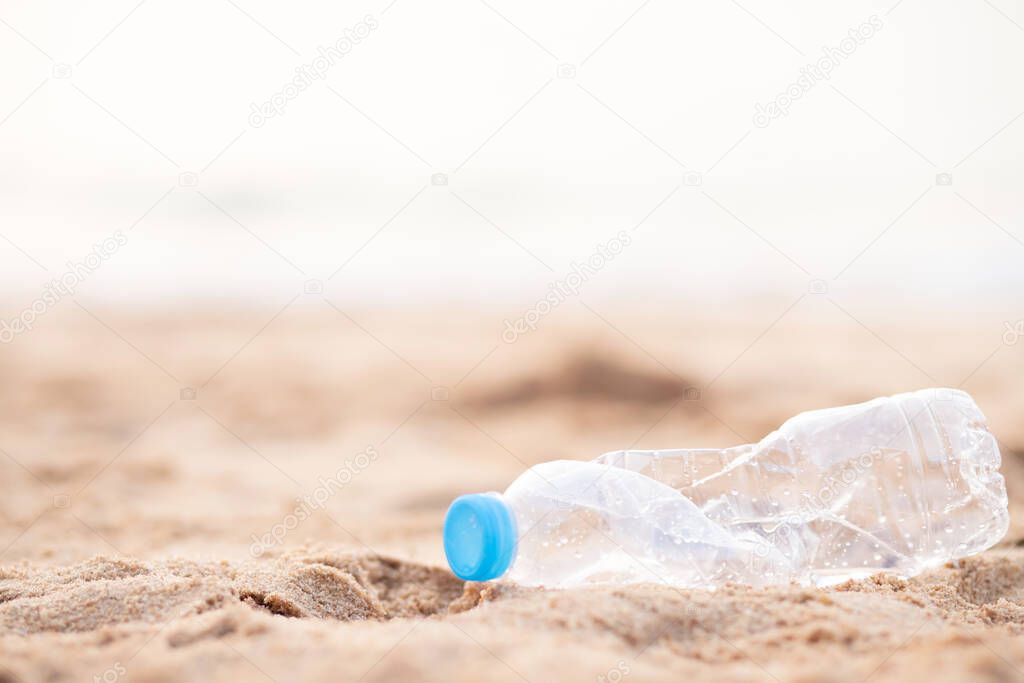 Human waste throw away junk water bottle on the sand, bring the sea to rot, leading to spoilage of the sea. beach garbage environmental damage causing global warming. soft focus.