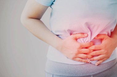 Tek renkli siyah beyaz görüntü mutsuz bir kadın mide ağrısı çekiyor karın bölgesindeki kırmızı renge odaklanıyor ve acı gösteriyor. konsept sağlık ve sağlık sorunu.