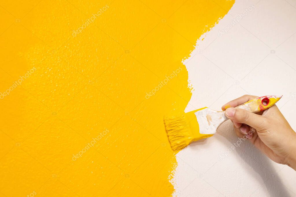 The mechanic is painting yellow on the wall.