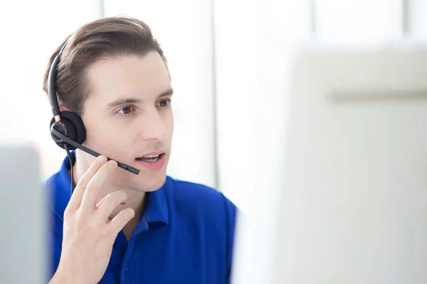 Man call-center agent with headset working on support hotline in the office