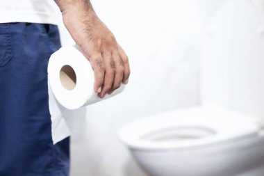 Adam ishalden muzdarip tuvalet kağıdını klozetin önünde tutuyor. Mide.