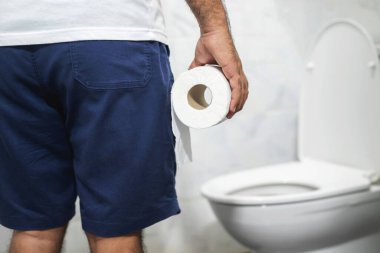 Adam ishalden muzdarip tuvalet kağıdını klozetin önünde tutuyor. Mide.