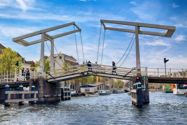 Haarlem, Nizozemsko - 30 duben 2017: Gravestenen padací most přes řeku Spaarne. Typické holandské architektury. Pohled z úrovně lodí. — Stock fotografie