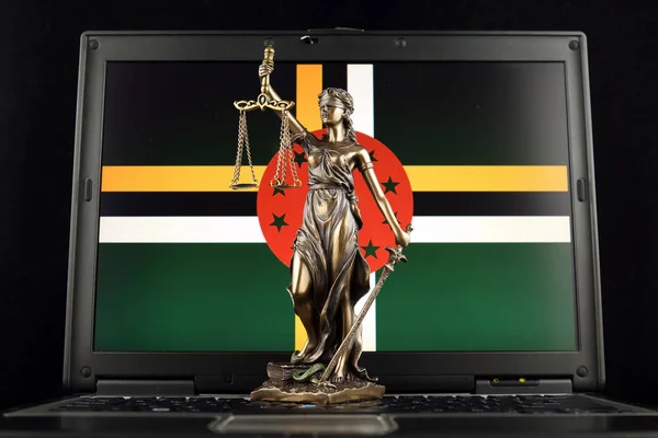 Symbol of law and justice with Dominica Flag on laptop. Studio shot.