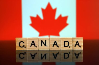 Kanada bayrağı ve küçük ahşap harflerden yapılmış bir ülke ismi. Stüdyo çekimi.