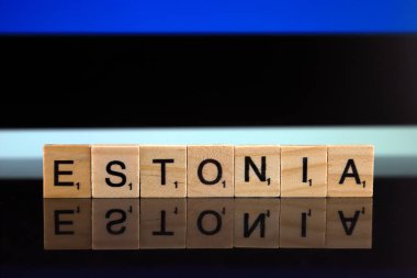 Estonya bayrağı ve küçük ahşap harflerden yapılmış bir ülke ismi. Stüdyo çekimi.
