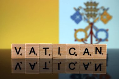 Vatikan Bayrağı ve küçük tahta harflerden yapılmış ülke adı. Stüdyo çekimi.