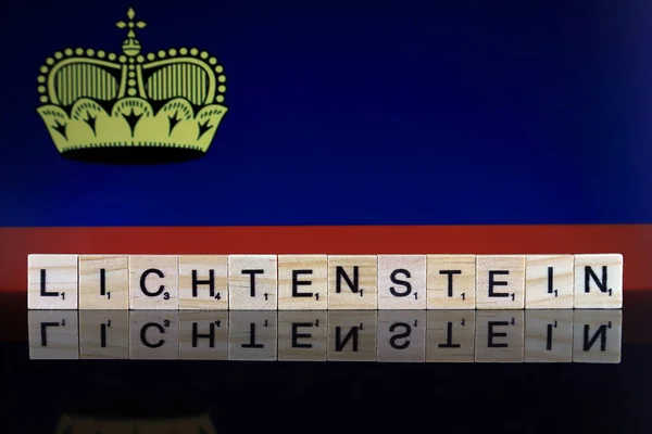 Lichtenstein Flag and country name made of small wooden letters. Studio shot.