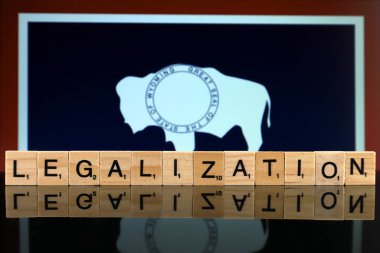 Wroclaw, Polonya - 4 Şubat 2020: Wyoming Eyalet Bayrağı ve küçük tahta harflerden yapılmış kelime yasallaştırma. Uyuşturucu politikası. Esrarın yasallaştırılması.