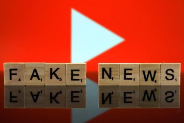 Wroclaw, Polonya - 12 Şubat 2020: Arka planda küçük tahta harflerden yapılmış Kelimeler Sahte Haberler ve Youtube logosu. Stüdyo çekimi.