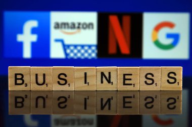 Wroclaw, Polonya - 12 Şubat 2020: Küçük ahşap harflerden yapılmış Word Business ve arka planda Facebook, Amazon, Netflix, Google logoları. Stüdyo çekimi.