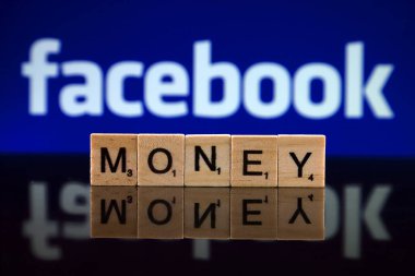 Wroclaw, Polonya - 12 Şubat 2020: Küçük tahta harflerden yapılmış Word Money ve arka planda Facebook logosu. Stüdyo çekimi.