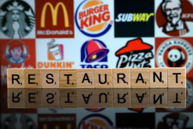 WROCLAW, POLAND - FEBRUARY 19, 2020: Word RESTAURANT made of wooden letters, and STARBUCKS, McDONALDS, BURGER KING, SUBWAY, KFC, WENDY'S, DUNKIN DONUTS, TACO BELL, PIZZA HUT, PANDA EXPRESS logos.