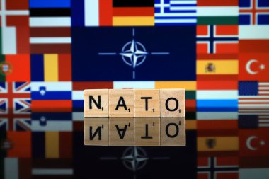 Wroclaw, Polonya - 19 Şubat 2020: Arkaplanda üye ülkelerin bayrakları bulunan Nato bayrağı (Kuzey Atlantik Anlaşması Örgütü) ve tahta harflerden oluşan kelime.