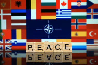 Wroclaw, Polonya - 19 Şubat 2020: Ahşap harflerden yapılmış Söz Barışı ve arka planda üye ülkelerin bayraklarıyla NATO Bayrağı (Kuzey Atlantik Antlaşması Örgütü).