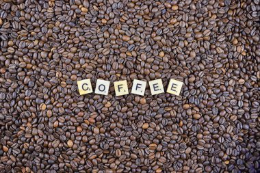 Wroclaw, Polonya - 25 Şubat 2020: Scrabble harflerinden yapılmış Word Coffee ve arka planda kahve taneleri. Lezzetli kahve severler için kavramsal imaj.