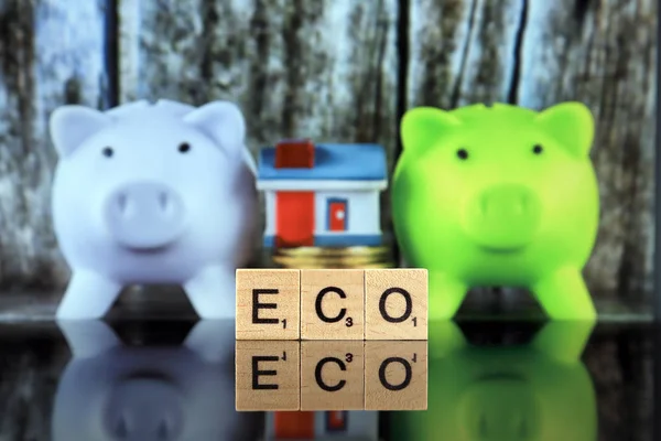 WROCLAW, POLAND - FEBRUARY 28, 2020: The word ECO made of scrabble letters, two piggy banks, coins and miniature house. Green eco renewable energy concept. Energy saving in the household.