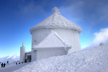 KARPACZ, POLAND - MARCH 08, 2020: St. Lawrence's Chapel in the Winter. A Roman Catholic chapel located on the peak of Sniezka mountain (1602 m. above sea level), Giant Mountains, Poland, Europe. clipart