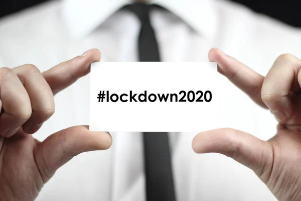 ホワイトのシャツを着たビジネスマンが Lockdown 2020 ハッシュタグ付き ソーシャルメディアで人気 という言葉で名刺を手にしている コロナウイルス Covid Global Disease — ストック写真