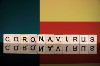 WROCLAW, POLAND - 28 Mart 2020: söz CORONAVIRUS ahşap harflerden yapılmış, ve arka planda Benin Bayrağı. Coronavirus (COVID-19) küresel hastalık 2020.