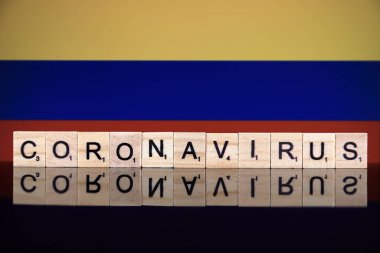 WROCLAW, POLAND - 28 Mart 2020: söz CORONAVIRUS ahşap harflerden yapılmış, ve arka planda Kolombiya Bayrağı. Coronavirus (COVID-19) küresel hastalık 2020.
