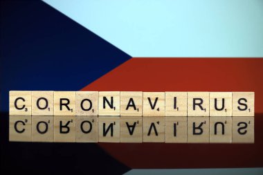 WROCLAW, POLAND - 28 Mart 2020: Kelime CORONAVIRUS ahşap harflerden yapılmış, ve arka planda Çek Cumhuriyeti Bayrağı. Coronavirus (COVID-19) küresel hastalık 2020.