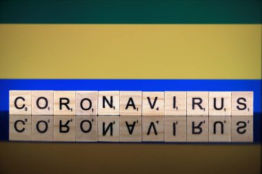 WROCLAW, POLAND - 28 Mart 2020: söz CORONAVIRUS ahşap harflerden yapılmış, ve arka planda Gabon Bayrağı. Coronavirus (COVID-19) küresel hastalık 2020.