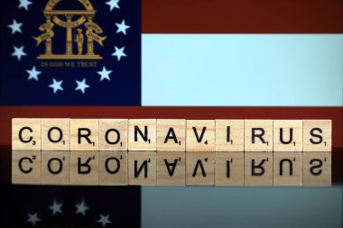 WROCLAW, POLAND - 28 Mart 2020: söz CORONAVIRUS ahşap harflerden yapılmış, ve arka planda Georgia State Flag. Coronavirus (COVID-19) küresel hastalık 2020.