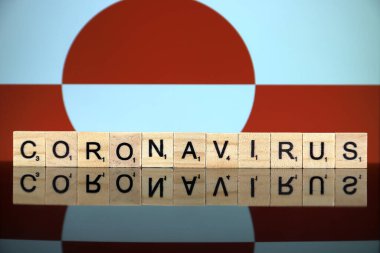 WROCLAW, POLAND - 28 Mart 2020: söz CORONAVIRUS ahşap harflerden yapılmış, ve arka planda Grönland Bayrağı. Coronavirus (COVID-19) küresel hastalık 2020.