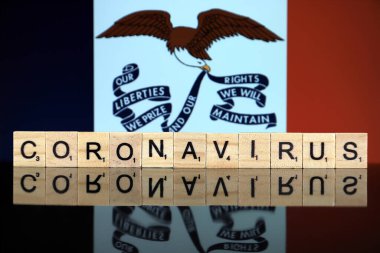WROCLAW, POLAND - 28 Mart 2020: söz CORONAVIRUS ahşap harflerden yapılmış, ve arka planda Iowa State Flag. Coronavirus (COVID-19) küresel hastalık 2020.