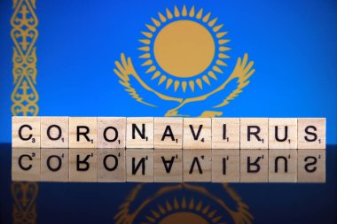 WROCLAW, POLAND - 28 Mart 2020: söz CORONAVIRUS ahşap harflerden yapılmış, ve arka planda Kazakistan Bayrağı. Coronavirus (COVID-19) küresel hastalık 2020.