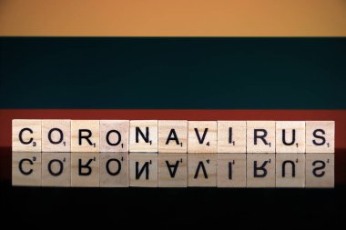 WROCLAW, POLAND - 28 Mart 2020: söz CORONAVIRUS ahşap harflerden yapılmış, ve arka planda Litvanya Bayrağı. Coronavirus (COVID-19) küresel hastalık 2020.