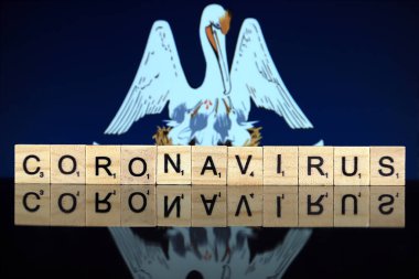WROCLAW, POLAND - 28 Mart 2020: söz CORONAVIRUS ahşap harflerden yapılmış, ve arka planda Louisiana State Flag. Coronavirus (COVID-19) küresel hastalık 2020.