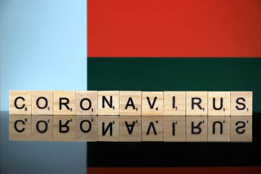 WROCLAW, POLAND - 28 Mart 2020: söz CORONAVIRUS ahşap harflerden yapılmış, ve arka planda Madagaskar Bayrağı. Coronavirus (COVID-19) küresel hastalık 2020.