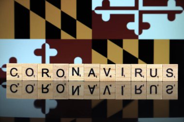 WROCLAW, POLAND - 28 Mart 2020: söz CORONAVIRUS ahşap harflerden yapılmış, ve Maryland State Flag arka planda. Coronavirus (COVID-19) küresel hastalık 2020.