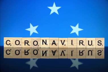 WROCLAW, POLAND - 28 Mart 2020: söz CORONAVIRUS ahşap harflerden yapılmış, ve arka planda Mikronezya Bayrağı. Coronavirus (COVID-19) küresel hastalık 2020.