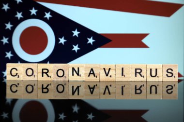 WROCLAW, POLAND - 28 Mart 2020: söz CORONAVIRUS ahşap harflerden yapılmış, ve Ohio State Flag arka planda. Coronavirus (COVID-19) küresel hastalık 2020.