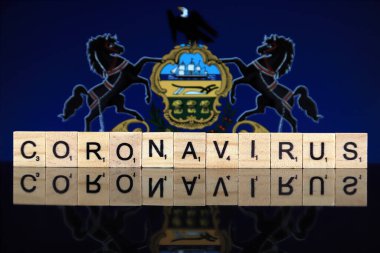WROCLAW, POLAND - 28 Mart 2020: söz CORONAVIRUS ahşap harflerden yapılmış, ve arka planda Pennsylvania Eyalet Bayrağı. Coronavirus (COVID-19) küresel hastalık 2020.