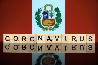 WROCLAW, POLAND - 28 Mart 2020: söz CORONAVIRUS ahşap harflerden yapılmış, ve arka planda Peru Bayrağı. Coronavirus (COVID-19) küresel hastalık 2020.