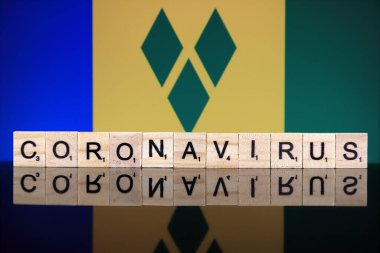 WROCLAW, POLAND - 28 Mart 2020: söz CORONAVIRUS ahşap harflerden yapılmış, ve arka planda Saint Vincent ve The Grenadines Flag. Coronavirus (COVID-19) küresel hastalık 2020.