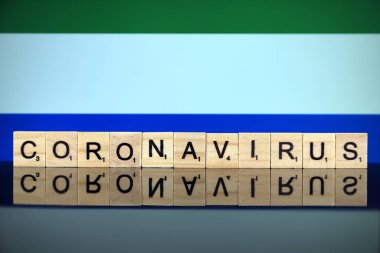 WROCLAW, POLAND - 28 Mart 2020: söz CORONAVIRUS ahşap harflerden yapılmış, ve arka planda Sierra Leone Bayrağı. Coronavirus (COVID-19) küresel hastalık 2020.
