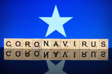 WROCLAW, POLAND - 28 Mart 2020: söz CORONAVIRUS ahşap harflerden yapılmış, ve arka planda Somali Bayrağı. Coronavirus (COVID-19) küresel hastalık 2020.