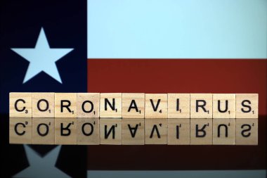 WROCLAW, POLAND - 28 Mart 2020: söz CORONAVIRUS ahşap harflerden yapılmış, ve arka planda Teksas Eyalet Bayrağı. Coronavirus (COVID-19) küresel hastalık 2020.