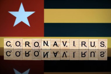 WROCLAW, POLAND - 28 Mart 2020: söz CORONAVIRus ahşap harflerden yapılmış, ve Togo Flag arka planda. Coronavirus (COVID-19) küresel hastalık 2020.