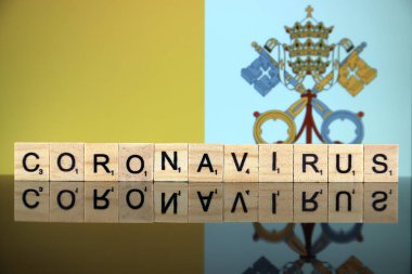 WROCLAW, POLAND - 28 Mart 2020: söz CORONAVIRUS ahşap harflerden yapılmış, ve arka planda Vatikan Şehir Bayrağı. Coronavirus (COVID-19) küresel hastalık 2020.