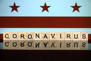 WROCLAW, POLAND - 28 Mart 2020: söz CORONAVIRUS ahşap harflerden yapılmış, ve arka planda Washington DC Bayrağı. Coronavirus (COVID-19) küresel hastalık 2020.